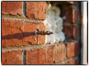 Professionele injectie van isolatieschuim in spouwmuur via boorgat, met injectiepistool en rode bakstenen zichtbaar